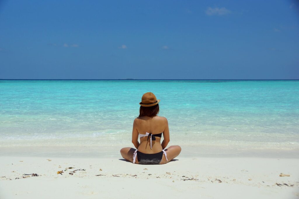 Woman Wearing Black and White Brassiere Sitting on White Sand